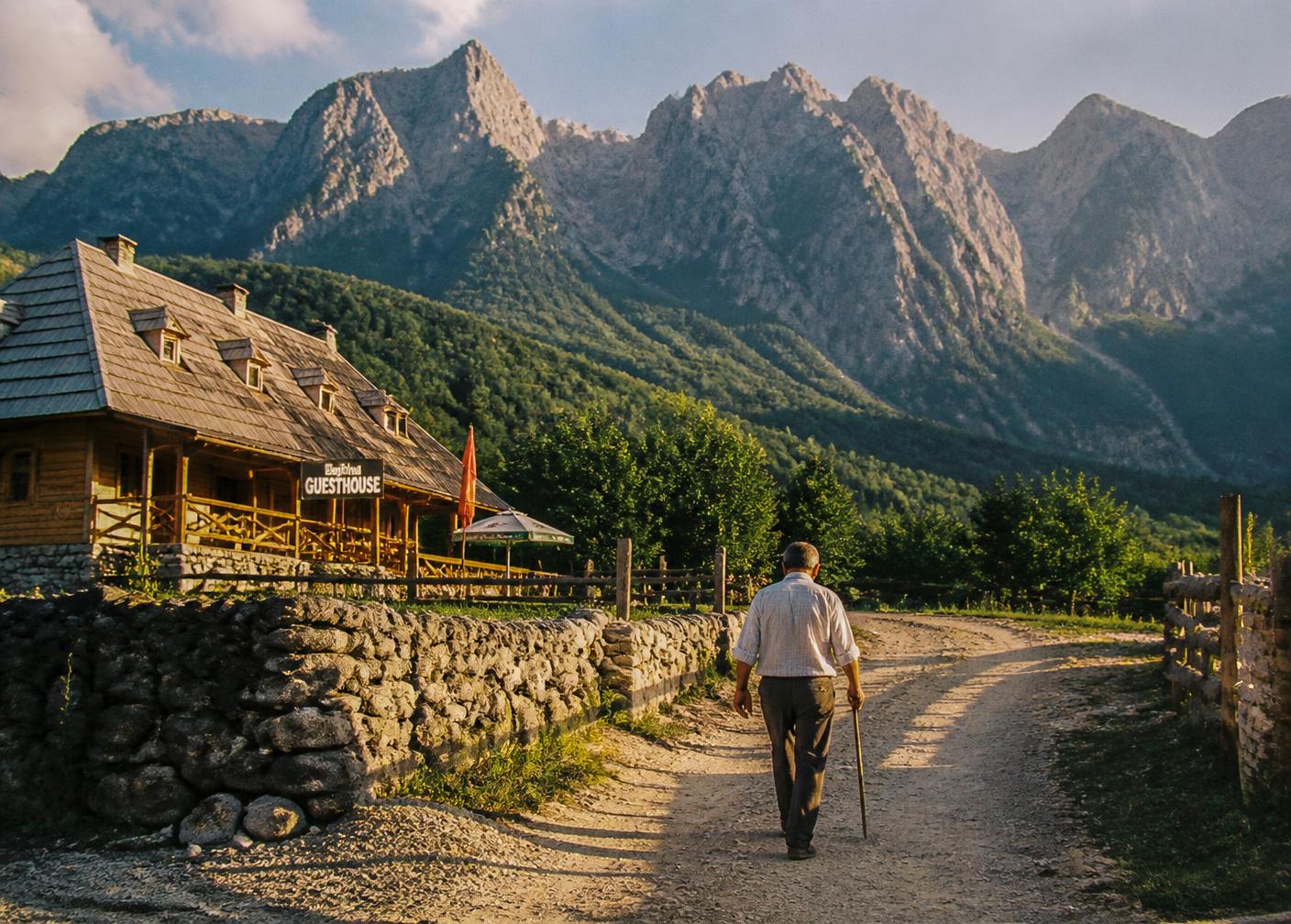 A wooden guesthouse on a dirt road below the limestone peaks above Theth, Albania